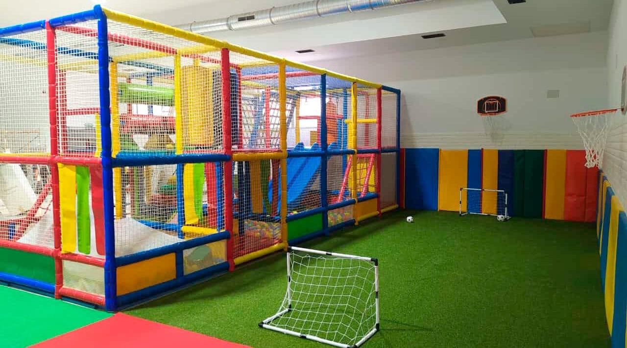 Parque infantil de dos alturas con canasta de baloncesto y campo de fútbol de césped artificial