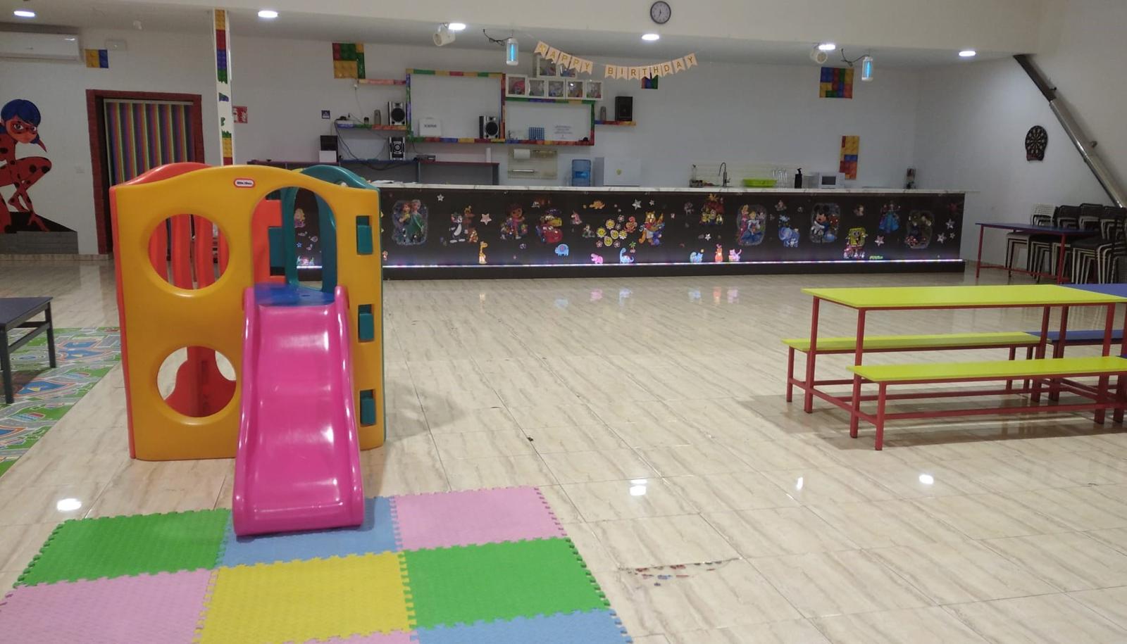 Zona con tobogán y parque infantil junto a mesas de celebración