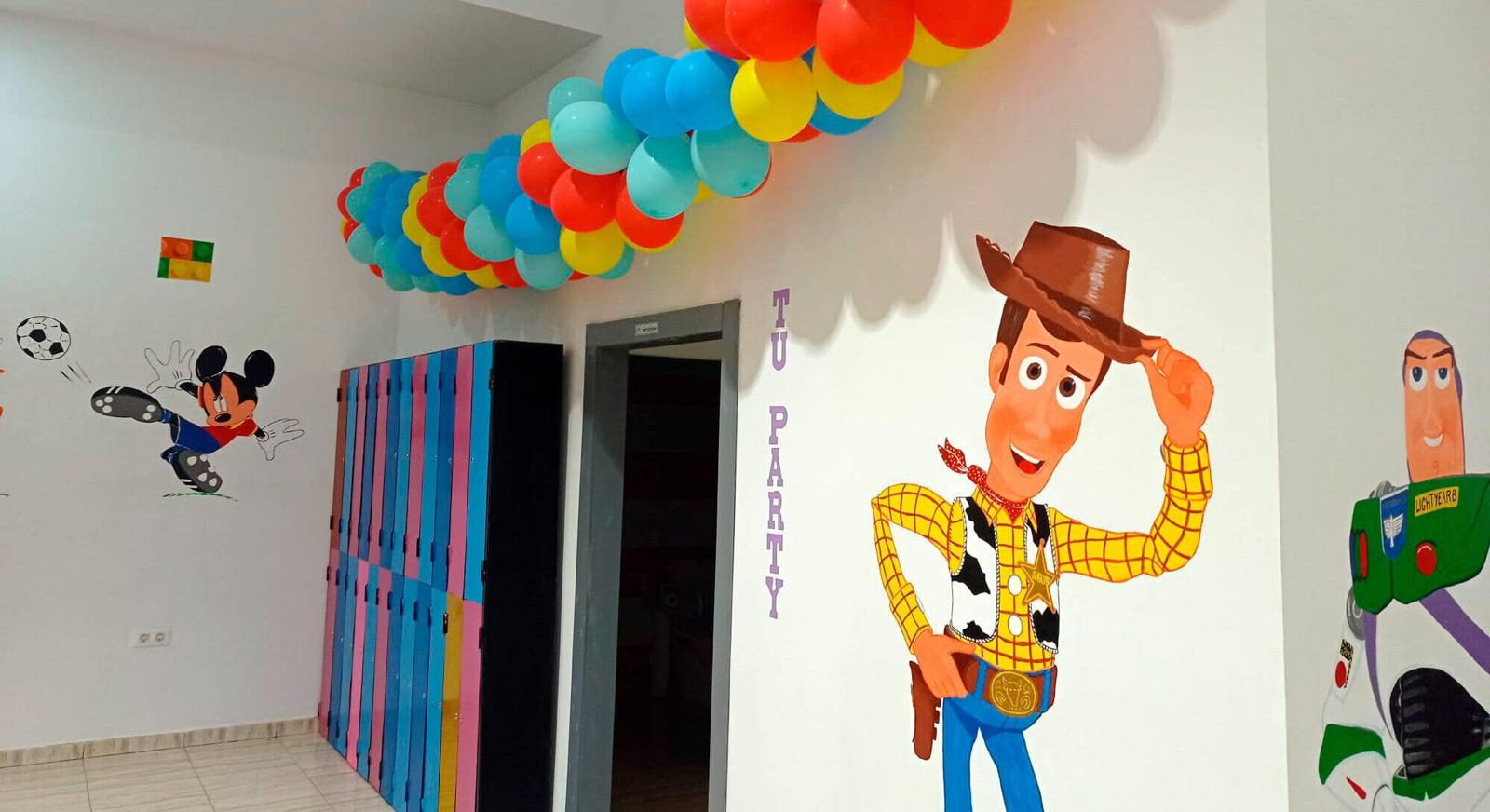Entrada decorada con globos y murales de Toy Story y Mickey Mouse