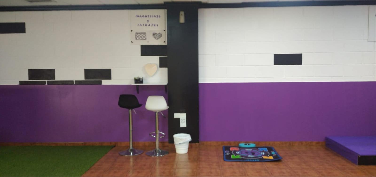 Zona de maquillaje y tatuajes con taburetes y decoración morada