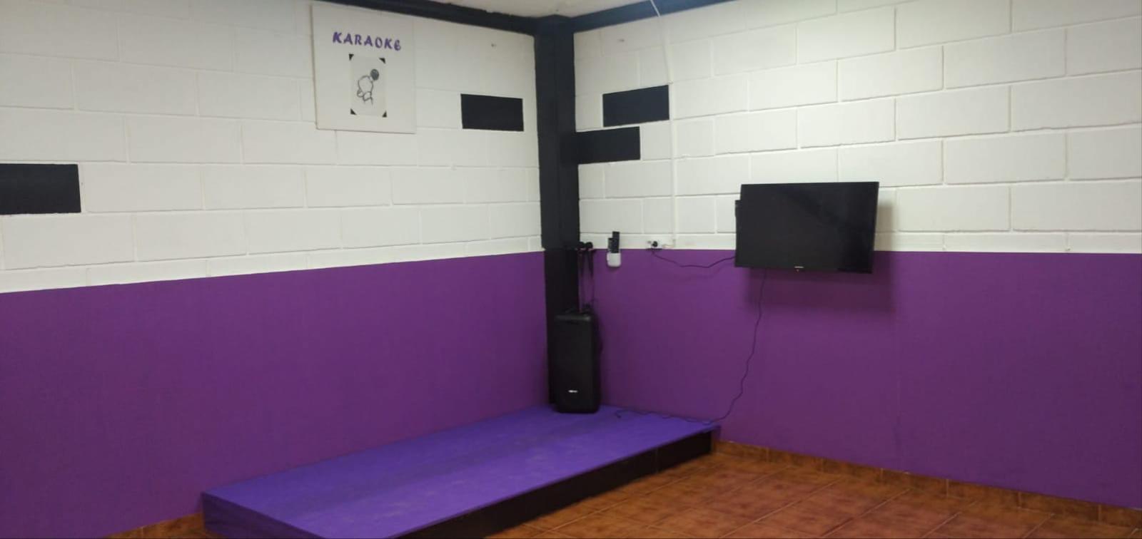Zona de karaoke con pantalla, altavoz y tarima morada