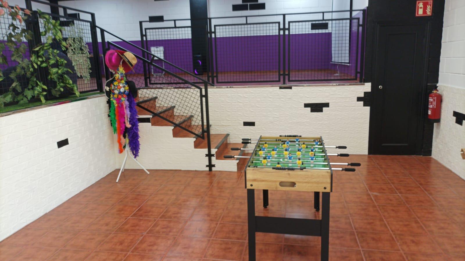 Zona de futbolín con disfraces y escalera a la planta superior